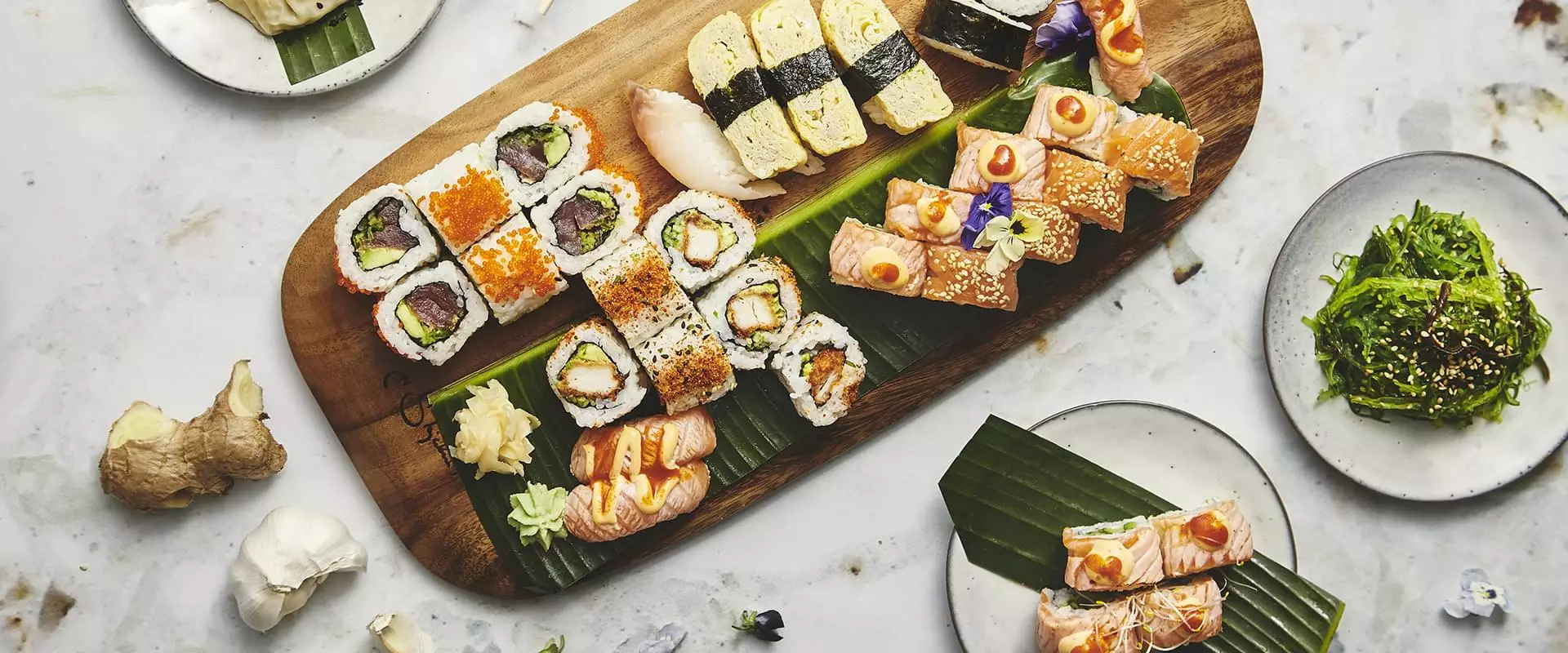 Selskab på sushirestaurant - Sushi på bambusblade og skærebræt